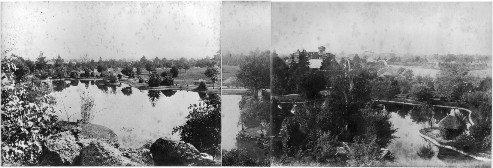 Black and white photograph from a high view point of a large lake in a garden surrounded by trees with a stately home beyond.