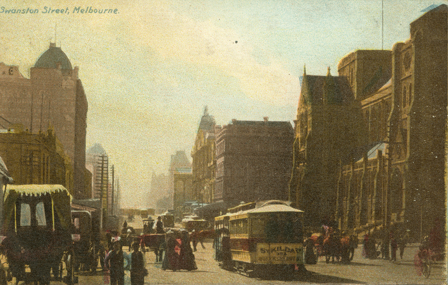 Tinted black and white photographic postcard looking along a Victorian city street a cathedral without spires on the right. A tramcar and pedestrians on the street.