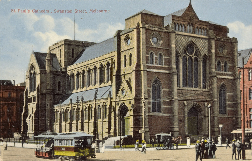 Tinted black and white photographic postcard of a Gothic Revival cathedral without spires on a street corner in an Edwardian city, a horse and carriage in front, a tramcar and pedestrians on the street.