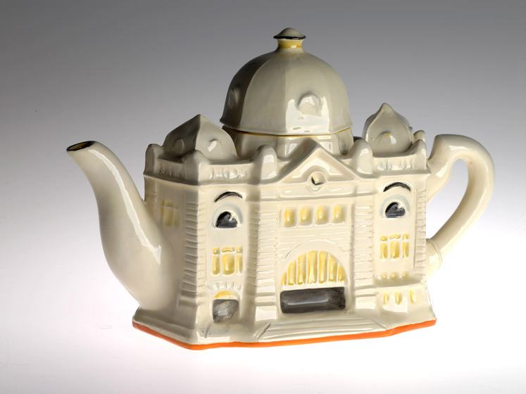 A ceramic teapot, designed to resemble a train station. The lid is domed and represents the roof of the station.