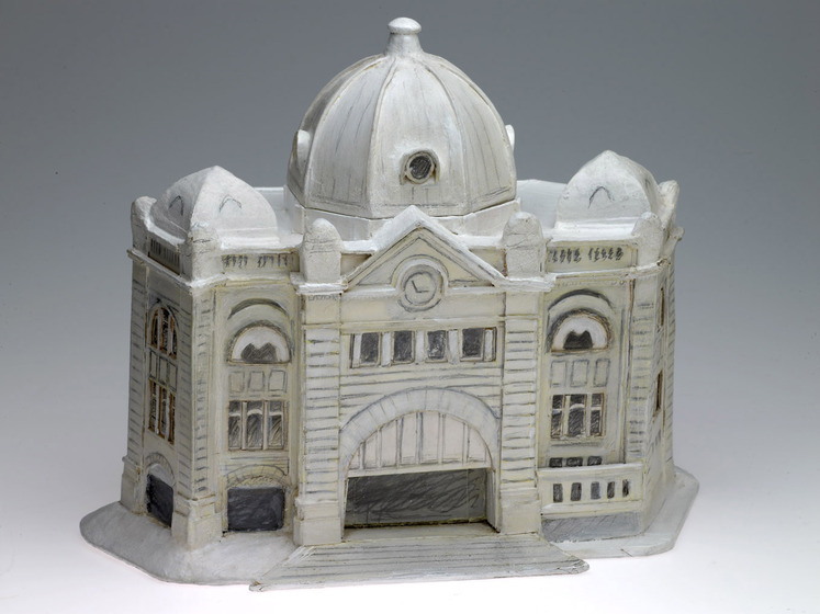 A cardboard model of a train station. The model is very detailed, with precise window and doors painted on all sides.