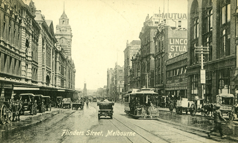 Postcard of a streetscape in Melbourne. Tall brick and sandstone buildings line both sides of the street. In the centre of the street, trams, cars and horse carriages are moving people.