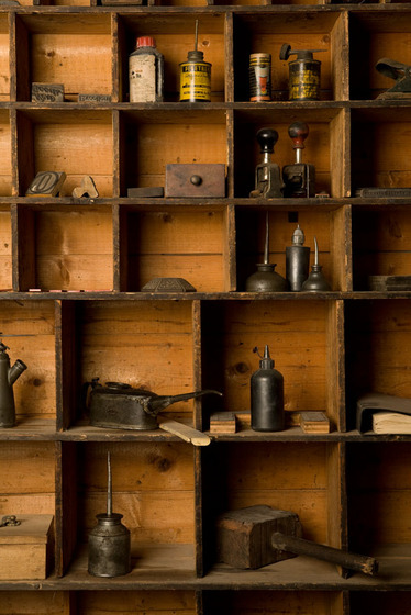 A set of square wooden shelves, all different sizes. In each square is a different type of equipment used in the printing trade.