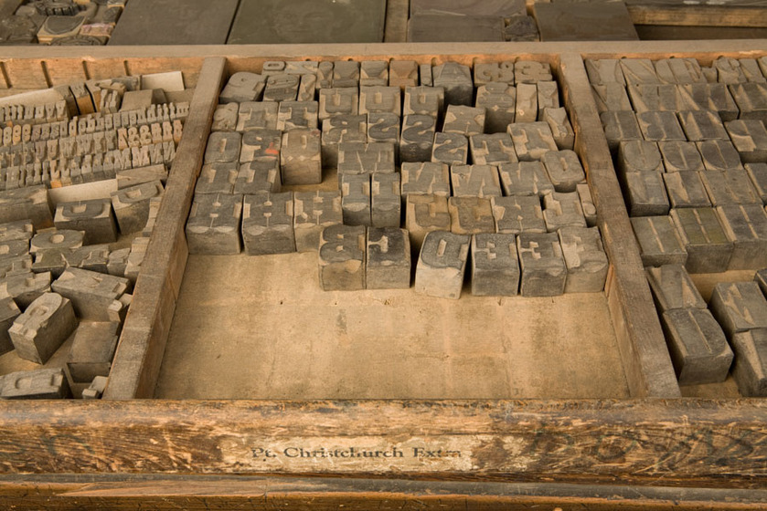 A wooden tray with three sections. In each section is a selection of wooden stamps with letters and numbers on them.