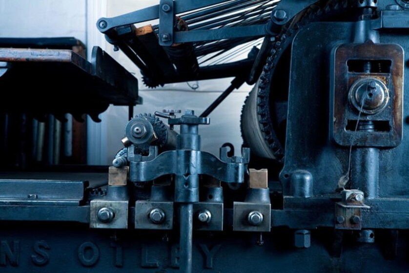 A large piece of metal machinery, The machine has lots of cogs and bolts holding the pieces together.