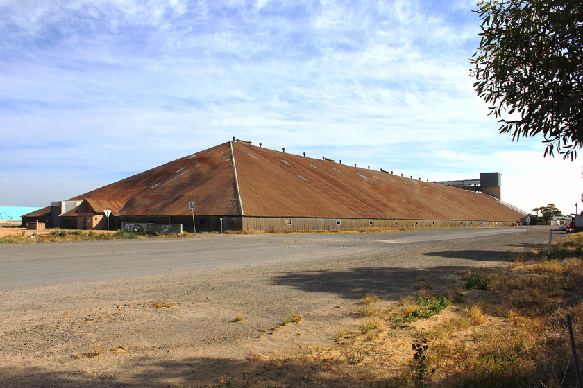 Exterior of a large grain shed with a severely sloped tin roof.