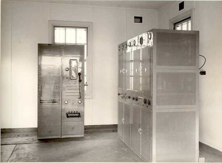 A room containing two large stand alone metal cupboards. On the front of each of the cupboards are dials and switches.