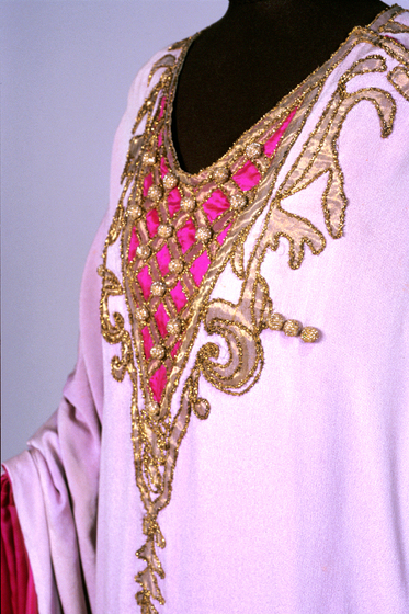 Zoomed in photograph of gold embroidered detailing on a pink gown. 