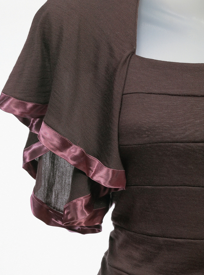 Detailed view of the sleeves of a brown jersey panelled dress with a brown satin ribbon trim