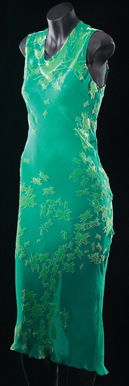 Mannequin wearing a green silk, bias-cut slip dress with ‘beetle’ embossing across the body