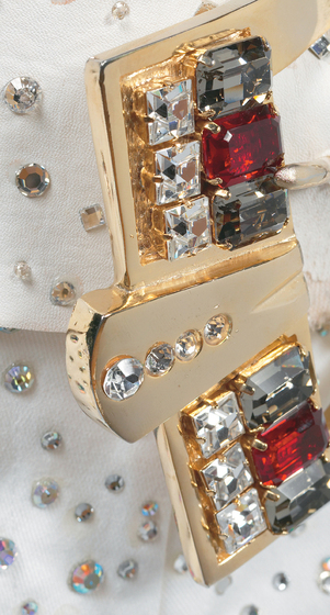 Gold belt buckle, covered in large crystals and grey and red gemstones.