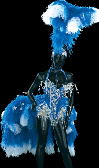 Mannequin wearing a decorative blue halter neck leotard, covered in blue ostrich feathers and star shaped jewels. The mannequin is also wearing a head dress that features a plume of blue and white ostrich feathers