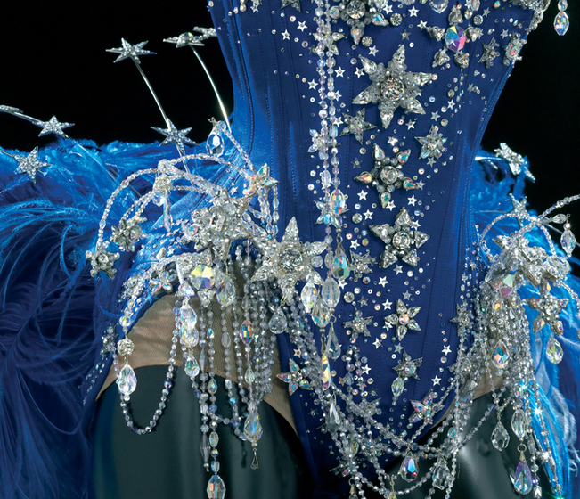 Close up of the blue bodice, covered in star shaped crystals and draping threads of jewels of differing sizes.
