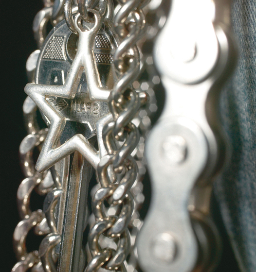 Detailed view of fringe patch, including silver chains, stars and a key
