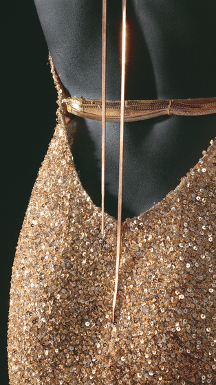 Detailed view of the back of the mannequin wearing a gold sequin mesh dress