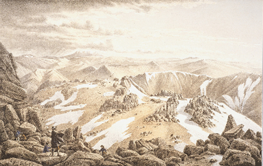 Four men stand at various points on a rocky outcrop, looking over a rolling valley with rock mounds and snow patches on the ground.