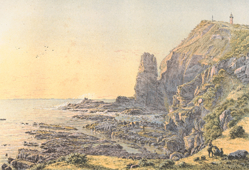 A rocky outcrop sits on the oceans edge, with scrub and trees lining the cliff edges. In the distance a small lighthouse can be seen on the hill.