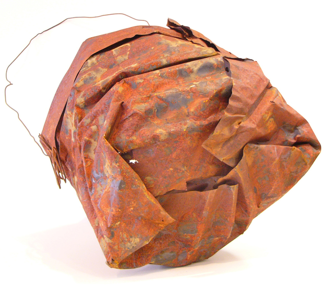 Sculpture of a basket using a large rusted piece of metal folded into each other to form the body and wire for the handle.