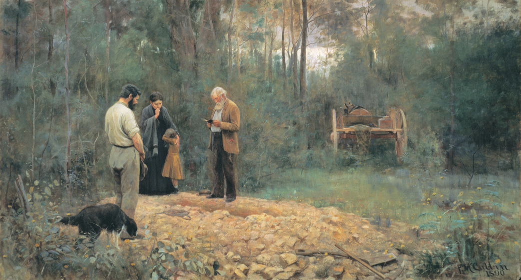 Three adults and a small child stand over a rocky grave sight. Their heads are bowed and one man reads from a small book. They are surrounded by bush and a wagon stands off to the side. A dog sniffs the pile of rocks around the grave.