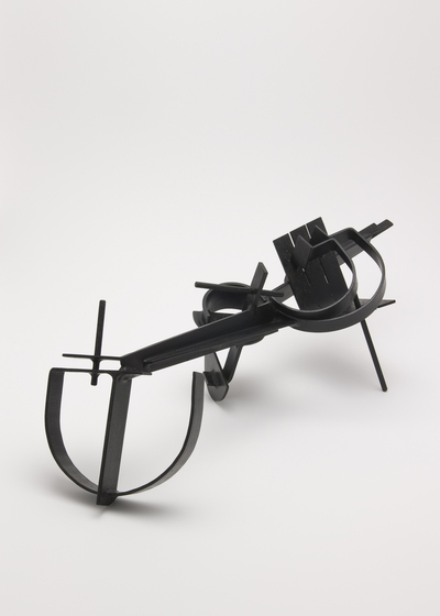 A black sculpture made of metal and featuring straight lines and semi circles, similar to stirrups