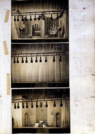 Three sepia photographs of different set designs, stuck to a scrapbook page. There are some hand written notes in the margin.