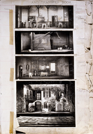 Four black and white photographs of different set designs, stuck to a scrapbook page. There are some hand written notes in the margin.
