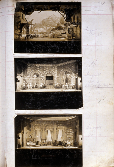 Three sepia photographs of different set designs, stuck to a scrapbook page. There are some hand written notes in the margin.