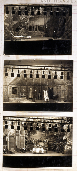 Three sepia photographs of different set designs, stuck to a scrapbook page. There are some hand written notes in the margin.