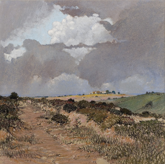 A landscape of an open field, a dirt channel running through the centre and low lying bushes and scrub on either side. In the background are rolling green and yellow hills, a small house on a hill and moody clouds circling above.