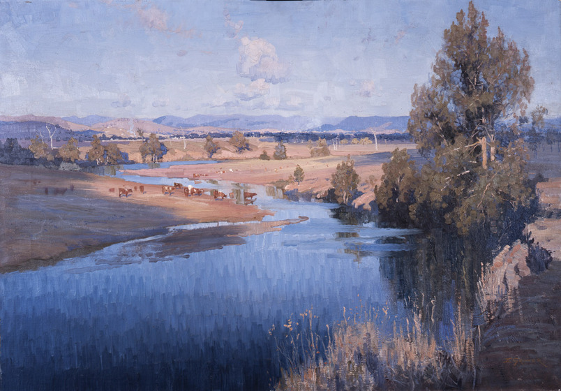 Landscape scene of a wide blue river, running through the countryside. Rolling flats run down to the waters edge, some parts covered in trees, some in grass, and some bare. Cattle can be seen grazing in the flats, some heading to the water to drink. In the distant background are rolling hills.