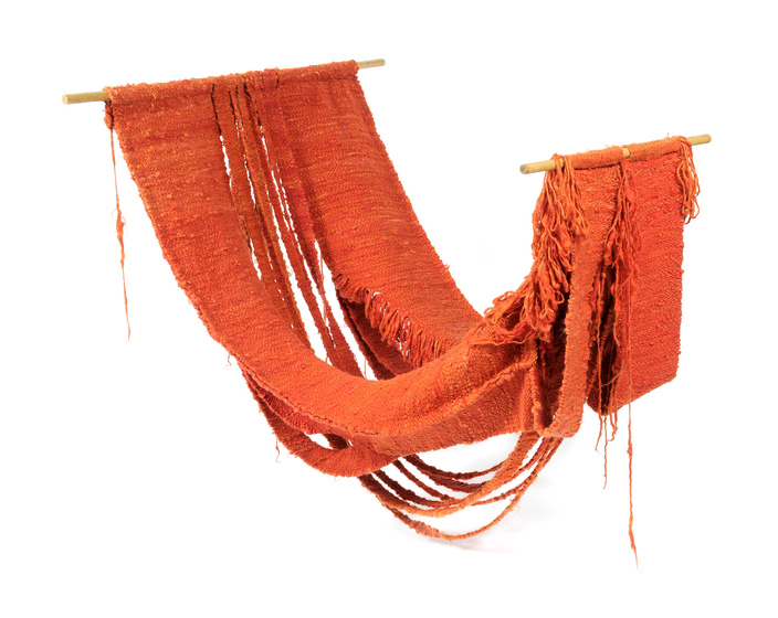 Large orange woven hammock styles artwork, hanging off two pieces of dowel from either end.
