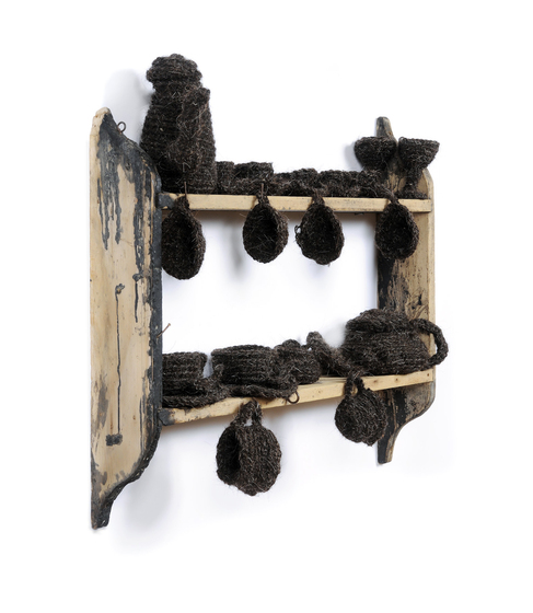 Small wooden wall shelf, made up of two shelves. On each of the two shelves are a series of cups and jugs, woven from horse hair.