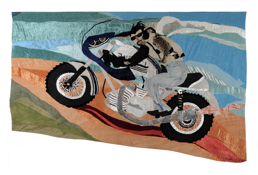 Appliqued textile image of a man riding a motorbike on a red dirt road, the sky and clouds behind him.