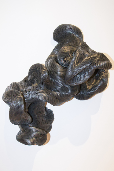 Silver woven material, coiled and wrapped over each other, almost resembling a snake curled up.