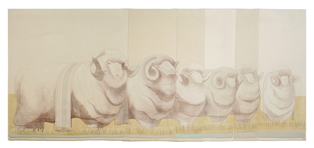 Six merino rams lined up on a row, the front ram with a prize ribbon slung over its back