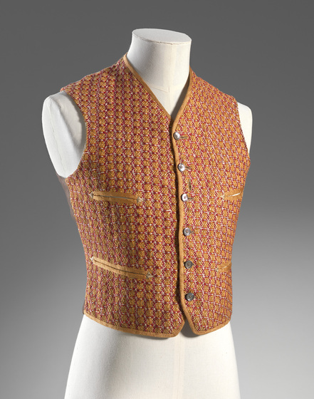 A patterned waistcoast with silver buttons down the centre, on a mannequin.