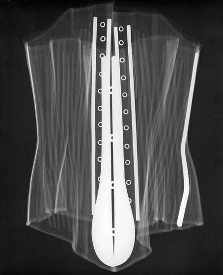 X-ray of a corset, with a faint outline of the structure and a vivid white area where the eyelets and attachments are.