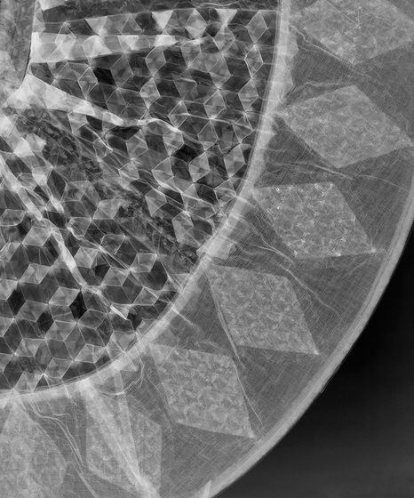 X-Ray image of a dolls skirt, with faint diamond pattern lines around the edge of the skirts base.