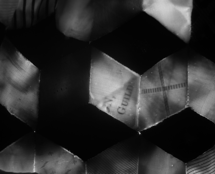 Detailed black and white image of the stitched paneling inside a dolls dress, including one small segment which reads 'guild'