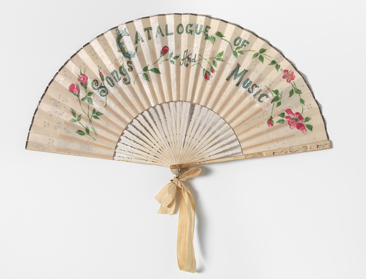 A silk hand fan, printed with floral patterns, the words 'Catalogue of Songs and Music' and tied in an outright positioned with a gold ribbon.