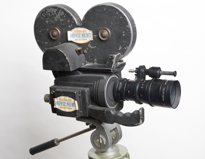 A silver 16mm film news camera positioned on a tripod.