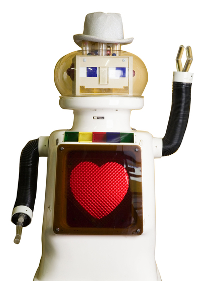 A small robot with a rounded square body with a love heart on its front, two black arms - one pointing up and one pointing down, and a small round head with a smiling face and tiny hat.
