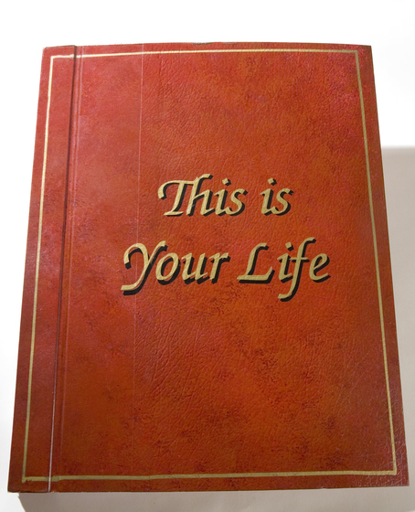 A brown leather book with gold square rim and the text 'This is Your life' in gold printing.