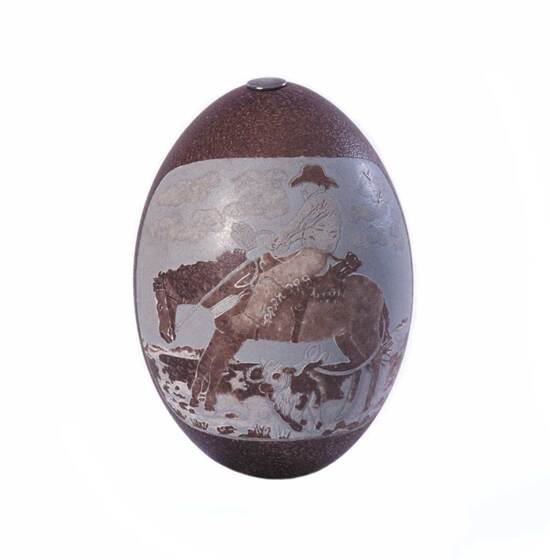A purple coloured emu egg with the image of a man on a horse, riding through a landscape, cows scattered in the landscape.