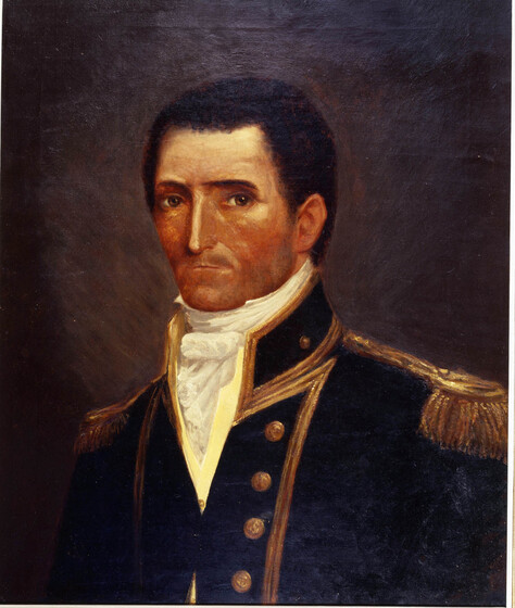 Portrait of a man in a decorative uniform, including brass buttons down the front of his jacket, gold trimming around the edges and golden tassels on the shoulders. He is wearing a white shirt with ruffled neck line, and a very serious look on his face.