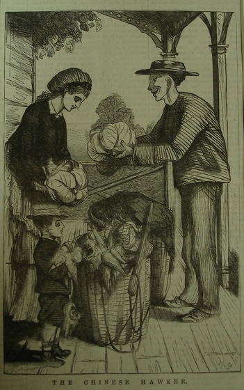 A man and a woman stand on the verandah of a house. The man is holding out a cabbage to the woman, whilst the woman also holds a cabbage and is looking down at it. At their feet are baskets filled with vegetables, and a small boy in a straw hat stands nearby and watches.