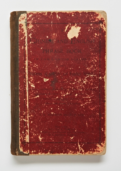 Front cover of a book, red in colour and black text across the front. There is lots of scratching and wear and tear, making the text hard to see.