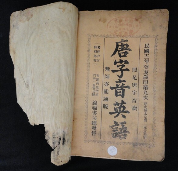 Inside front cover of a book, the left hand side slight damaged and torn, and the right hand side featuring Cantonese characters and some water damage and mould.