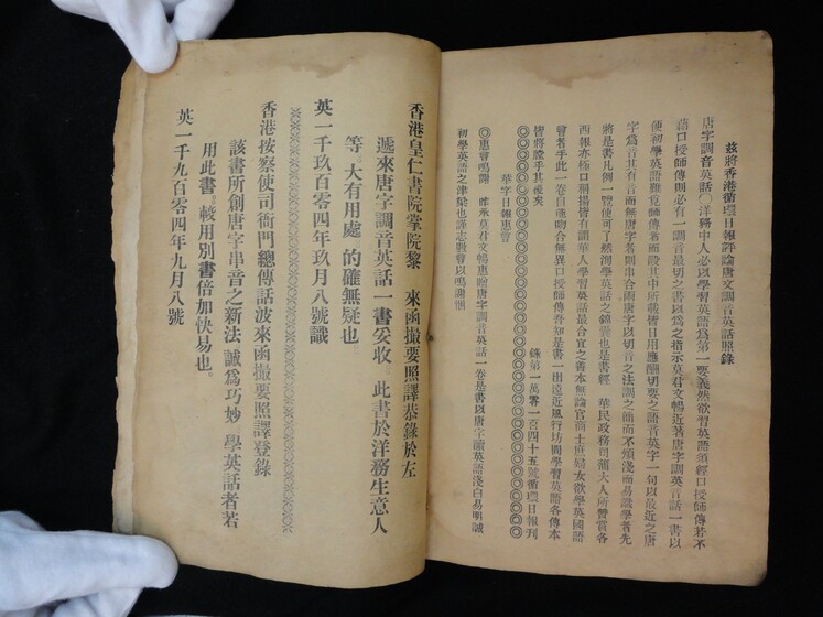 Double page book with Cantonese characters on both sides, being held by hands in white gloves.