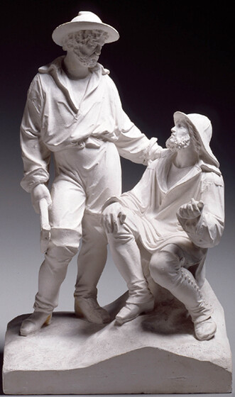A white stone sculpture of two men, one standing and one sitting. Both are wearing clothes seen frequently on the gold fields. The man standing has his hand resting on the shoulder of the sitting man.